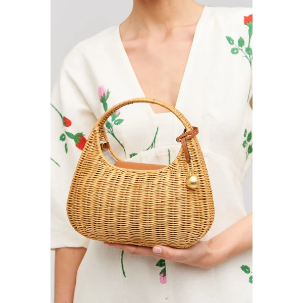 Profile view of model wearing the Oroton Clara Wicker Mini Bag in Natural/Cognac and Woven wicker exterior for Women