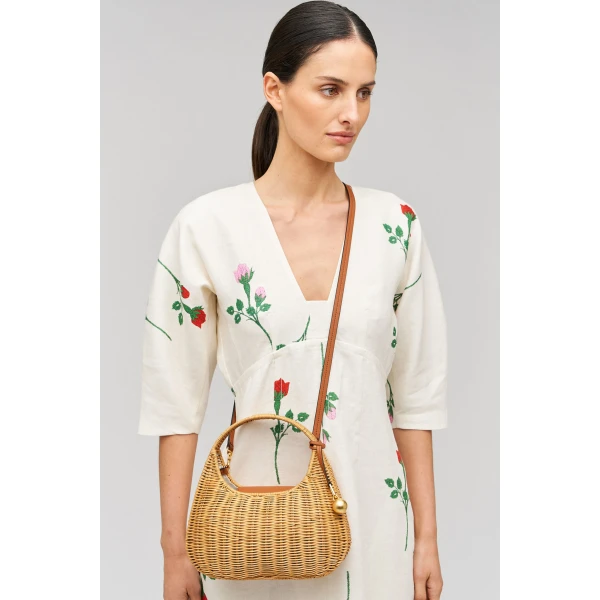 Profile view of model wearing the Oroton Clara Wicker Mini Bag in Natural/Cognac and Woven wicker exterior for Women