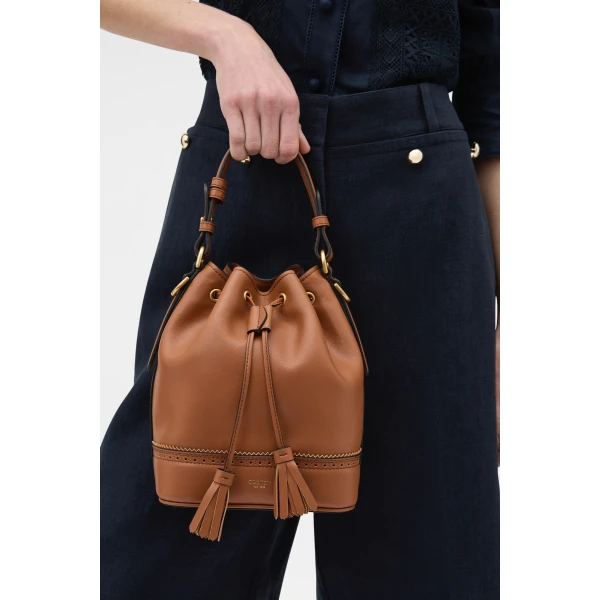 Profile view of model wearing the Oroton MAGGIE BUCKET BROGUING in COGNAC and Premium smooth leather for Women