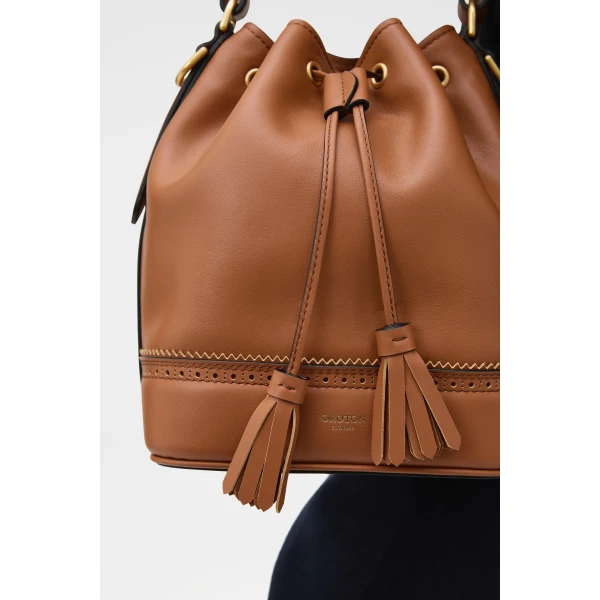 Profile view of model wearing the Oroton MAGGIE BUCKET BROGUING in COGNAC and Premium smooth leather for Women
