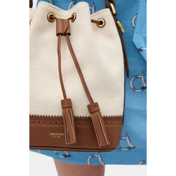 Profile view of model wearing the Oroton MAGGIE BUCKET CANVAS BROGUING in NATURAL/PENNY BROWN and Premium canvas material for Women
