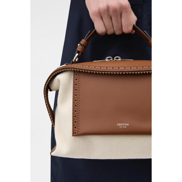 Profile view of model wearing the Oroton MICA BOWLER CANVAS BROGUING in NATURAL/PENNY BROWN and Premium canvas material for Women