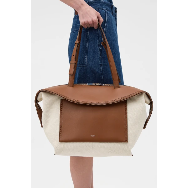 Profile view of model wearing the Oroton MICA MEDIUM TOTE CANVAS BROGUING in NATURAL/PENNY BROWN and Premium canvas material for Women