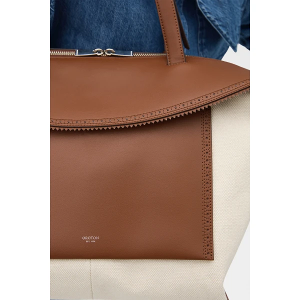 Profile view of model wearing the Oroton MICA MEDIUM TOTE CANVAS BROGUING in NATURAL/PENNY BROWN and Premium canvas material for Women