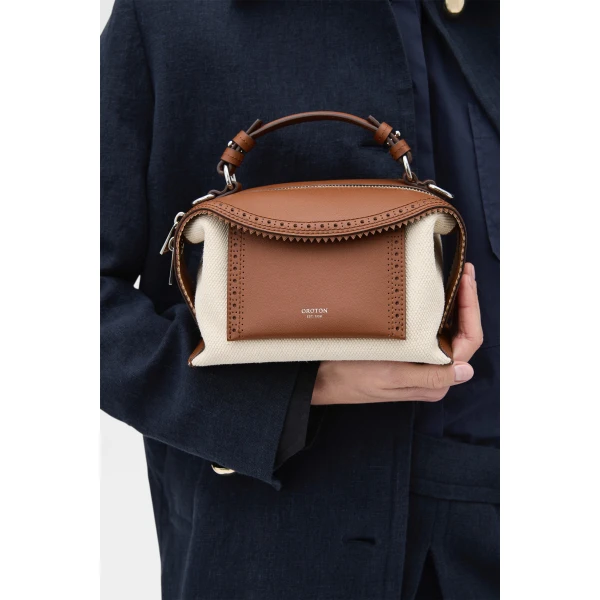 Profile view of model wearing the Oroton MICA MINI BOWLER CANVAS BROGUING in NATURAL/PENNY BROWN and Premium canvas material for Women