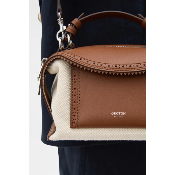 Profile view of model wearing the Oroton MICA MINI BOWLER CANVAS BROGUING in NATURAL/PENNY BROWN and Premium canvas material for Women