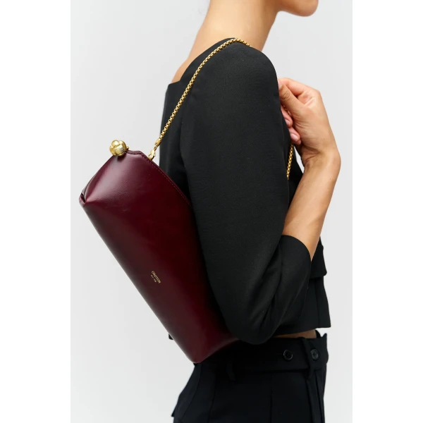 Profile view of model wearing the Oroton NAIA CLUTCH in CURRANT and Premium crackle leather for Women