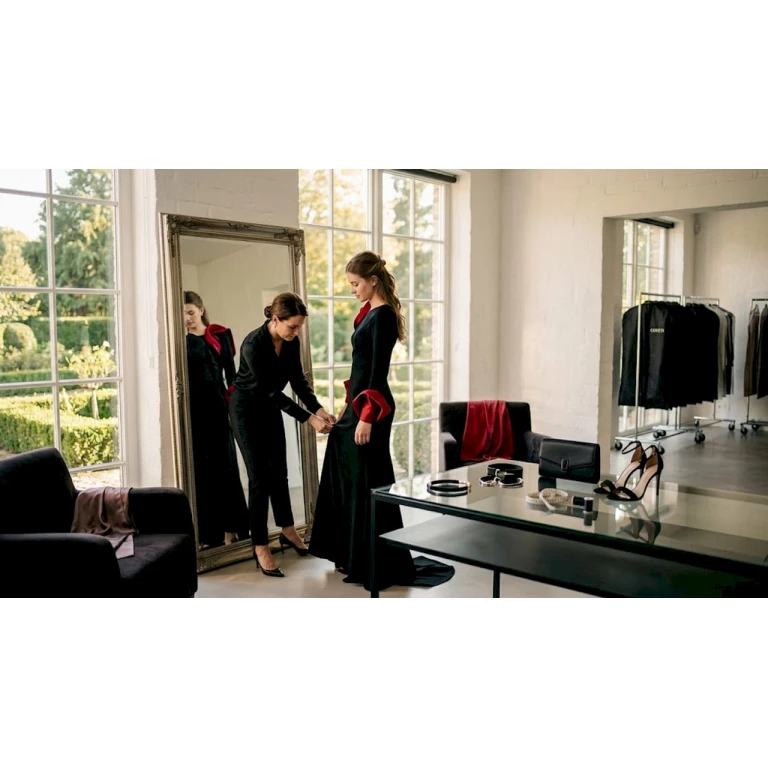Una stylist sistema con cura un abito da gala all’interno dello showroom.