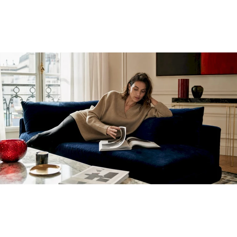 Installée confortablement chez elle, une femme explore les dernières tendances de la mode de luxe sur son ordinateur.