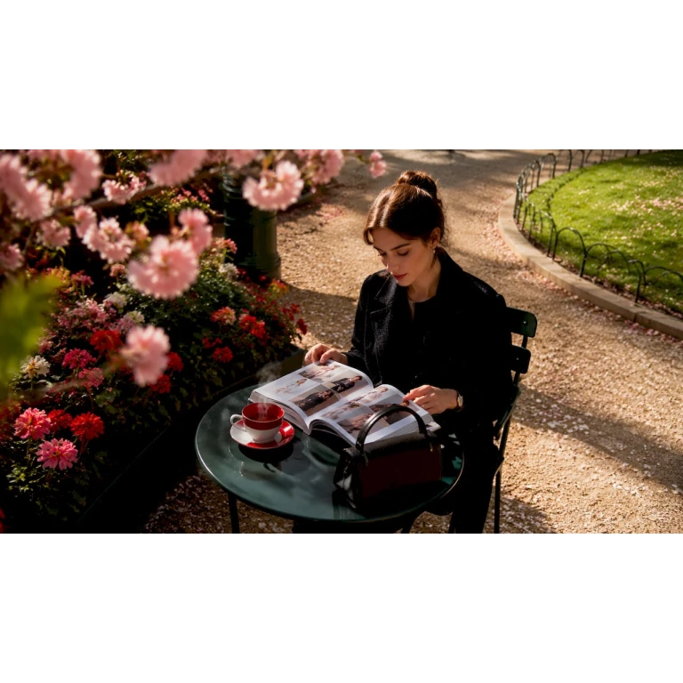 O femeie răsfoiește cele mai noi colecții de modă de lux, relaxându-se la o cafenea cochetă.